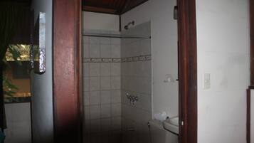 A small bathroom with a shower, toilet, and a towel rack.