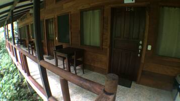 A wooden building with a covered porch, a door labeled "154", and a small table with chairs.