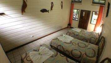 A room with two beds, a tiled floor, and wall-mounted decorations.