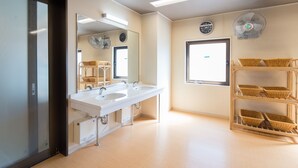 A modern bathroom with two sinks, a large mirror, a clock, a window, and wicker baskets on shelves. - Tabist Hotel Tetora Kitakyusyu (Kitakyushu)