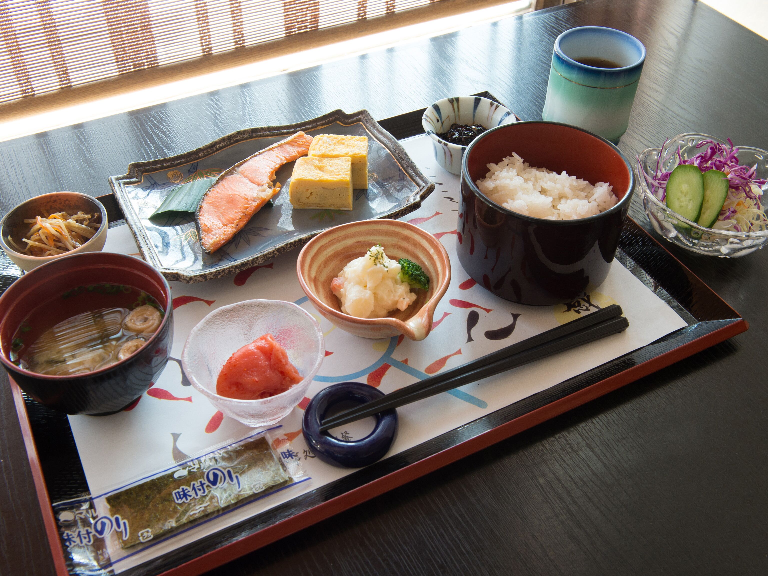 Un menú tradicional japonès presentat en una bandeja, amb diferents plats com ara arròs, salmó i verdures.