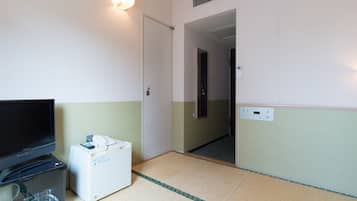 Quarto de hotel com televisão, minibar, porta e ar condicionado fixado na parede.