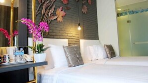 A hotel room with a bed, bedside tables, a mirror, and a wall with leaf patterns.