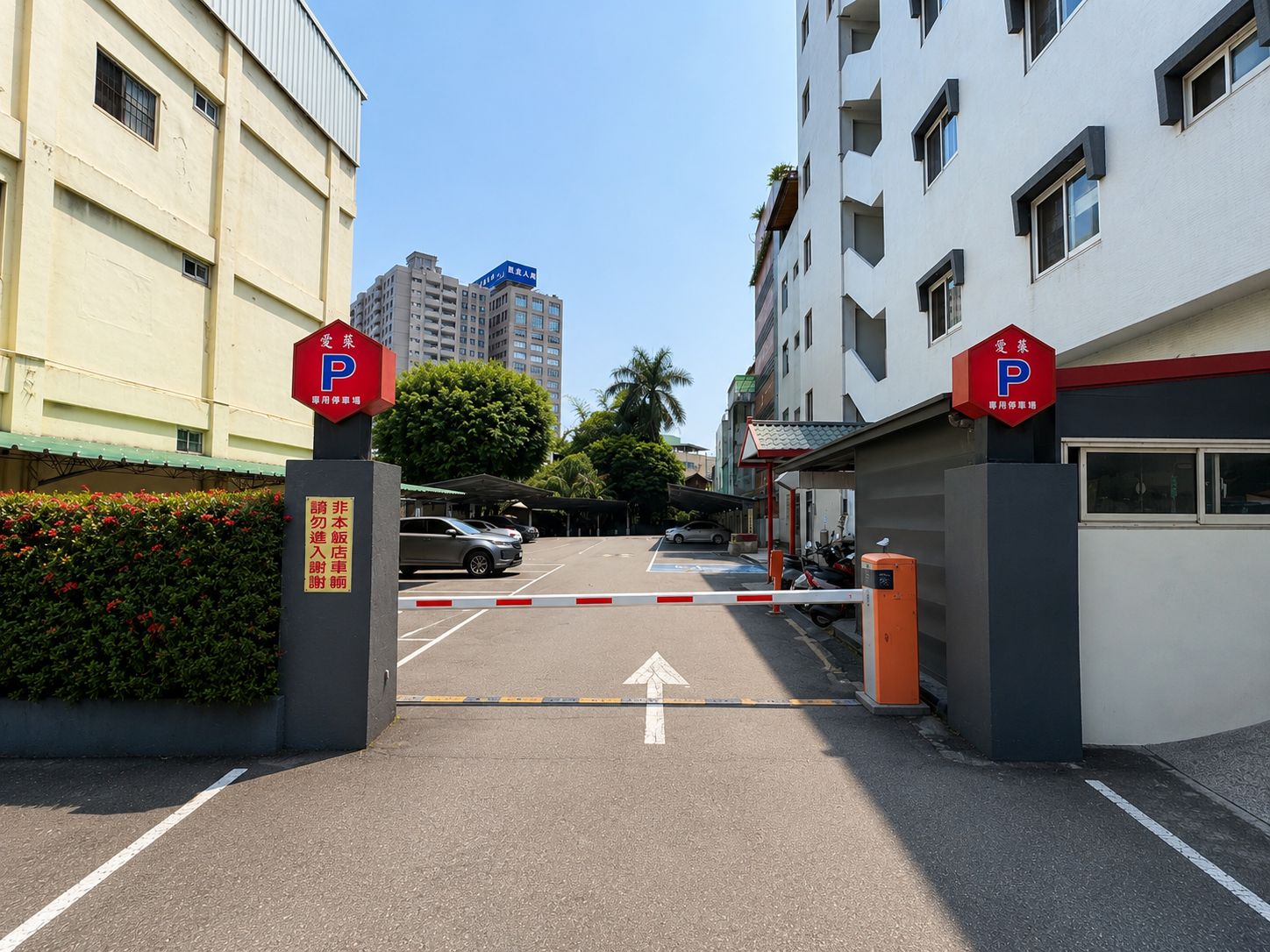 Ein begrenzter Parkeingang mit einem klaren Weg zu einem Parkplatz, umgeben von Gebäuden und Grünflächen.