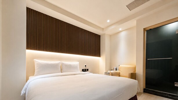 Une chambre d’hôtel avec un grand lit, une table de chevet avec une lampe, une armoire et une porte coulissante.