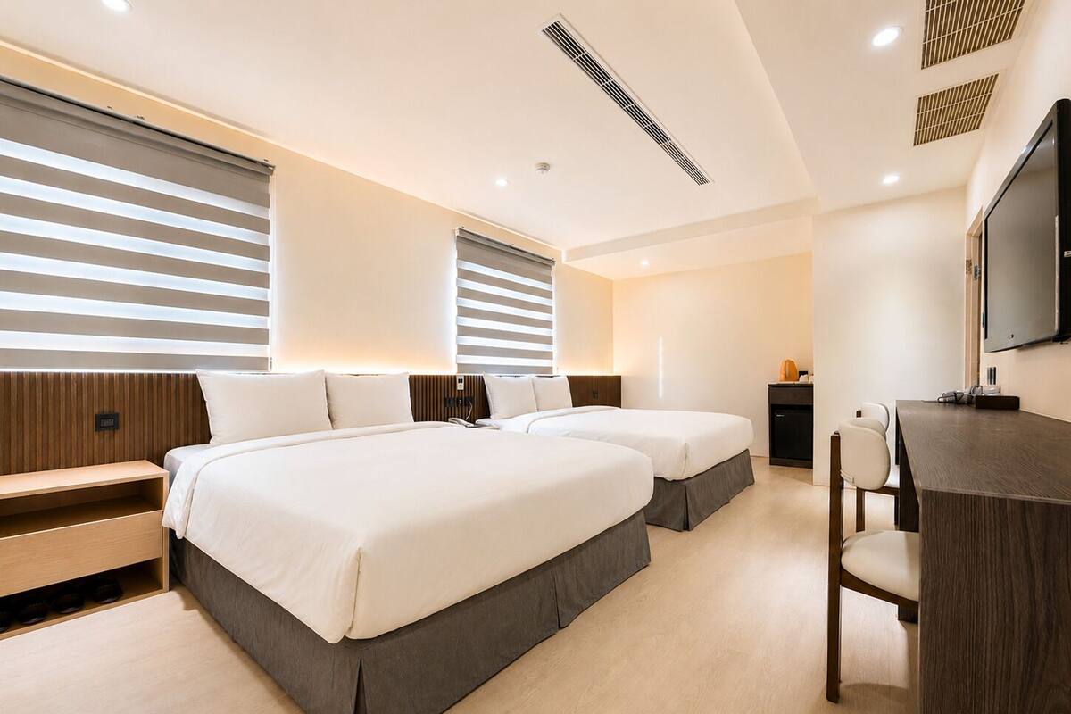 Une chambre d’hôtel avec deux lits, un bureau, une chaise, une télévision et un mini-bar.
