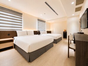 A hotel room with two beds, a desk, a chair, a TV, and a minibar. - Ai Lai Fashion Hotel (Taichung)