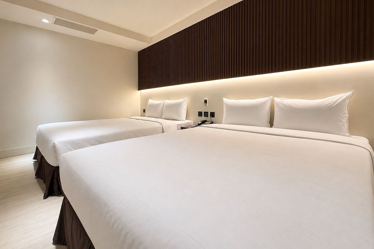 Een hotelkamer met twee bedden, een houten paneelwand en een modern design.