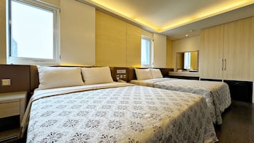 A hotel room with two beds, bedside tables, a mirror, and a wardrobe.