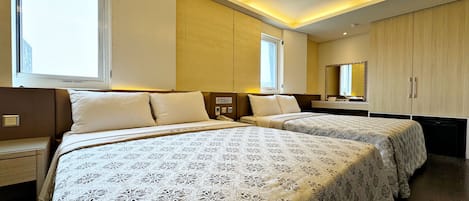 A hotel room with two beds, bedside tables, a mirror, and a wardrobe.