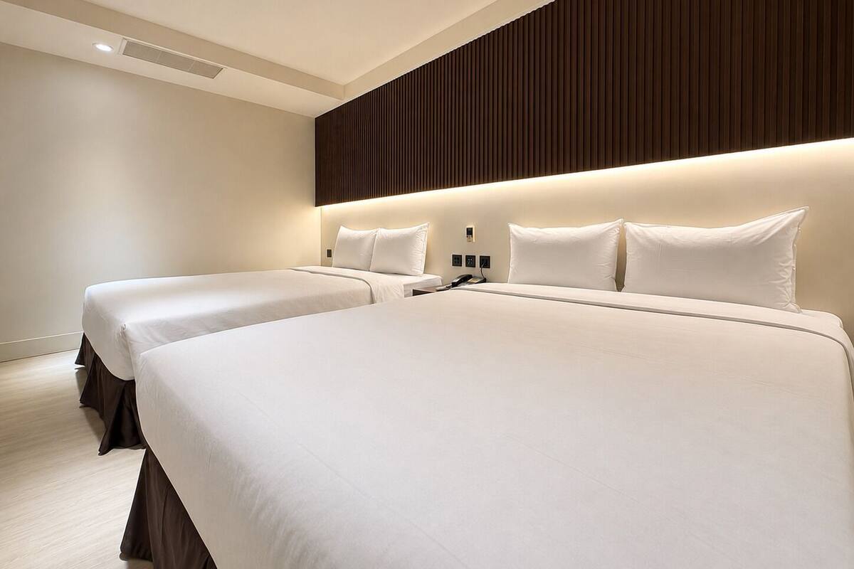Une chambre d’hôtel avec deux lits, un mur recouvert de panneaux en bois et un design moderne.