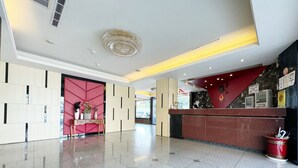 Un hall d’hôtel moderne avec un comptoir d’accueil, un mur décoratif et un grand lustre.