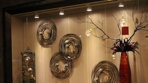 Une exposition d’objets décoratifs comprenant des spirales en métal et un vase orné de branches.