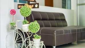 A modern living room with a dark leather sofa, decorative potted plants, and a 'Welcome' sign. - Be My Guest (Ubon Ratchathani)