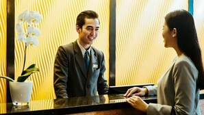 A reception desk with a man in a suit and a woman standing beside it. - Beston Hotel Palembang (Palembang)