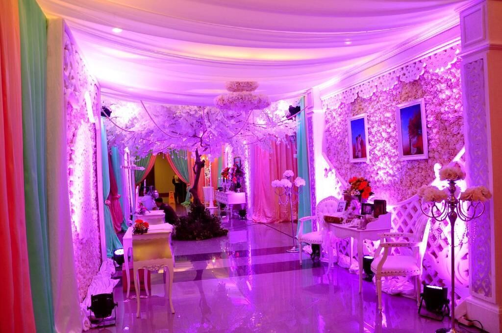 Una habitación con una silla blanca, una pequeña mesa y una pared decorativa.