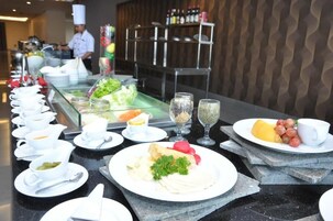 A buffet setup with various dishes, including salads, fruits, and beverages.