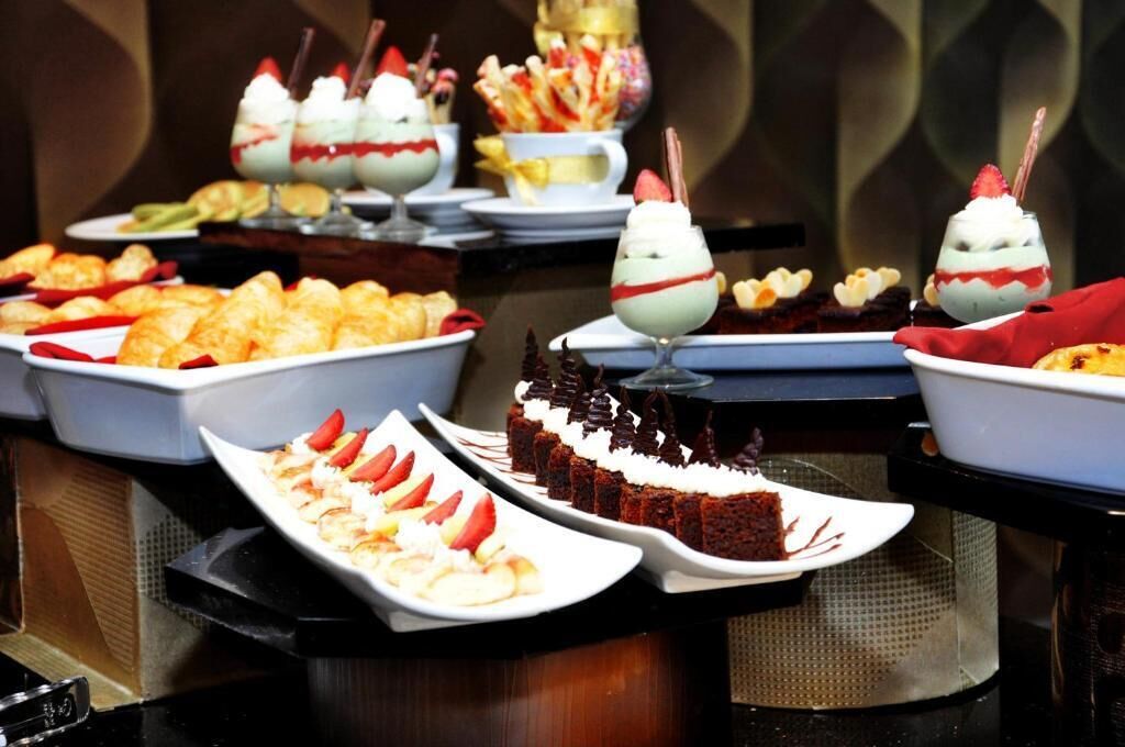 A buffet with various desserts including cakes, pastries, and fruit arrangements.