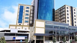 A modern building with a glass facade and a sign reading "Sudirman City Centre". - Beston Hotel Palembang (Palembang)