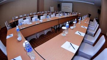 A conference room with a long table, chairs, water bottles, and a projector screen.