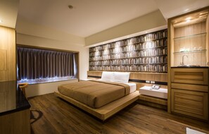 A modern bedroom with a large bed, a built-in bookshelf, a vanity with a mirror, and a window with curtains.