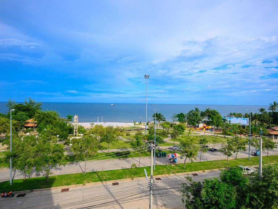 Un paisaje urbano costero con playa, áreas verdes y cielo despejado.