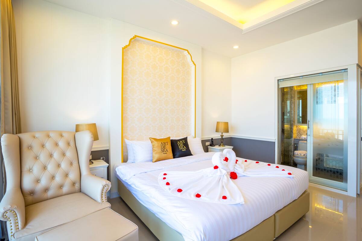 A spacious bedroom with a large bed, a plush armchair, and a walk-in closet.