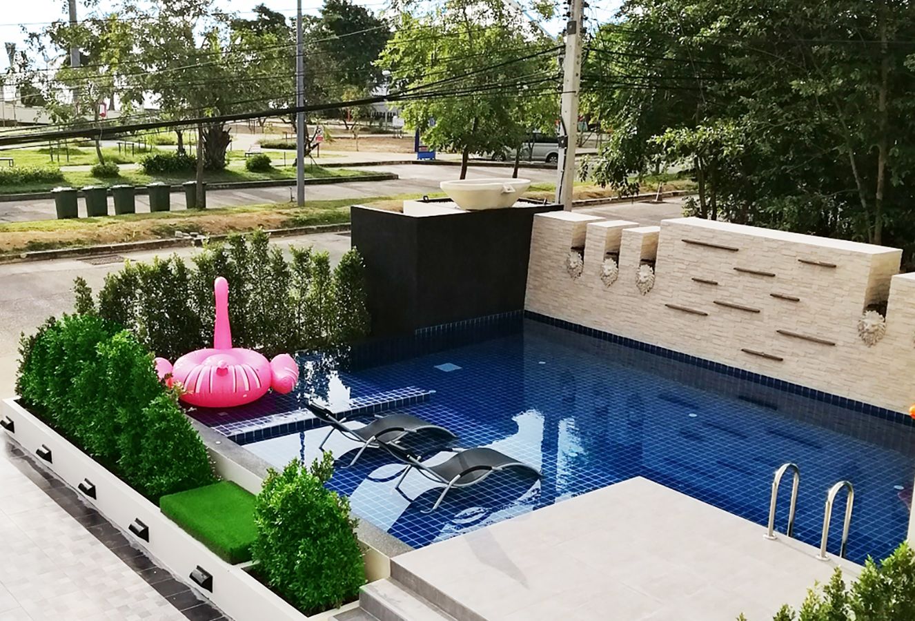 A swimming pool with a tiled deck, lounge chairs, and a pink decorative object.