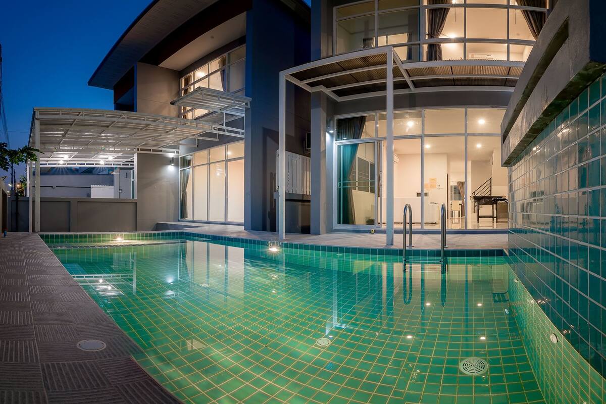 A modern building with a swimming pool, large windows, and a covered outdoor area.