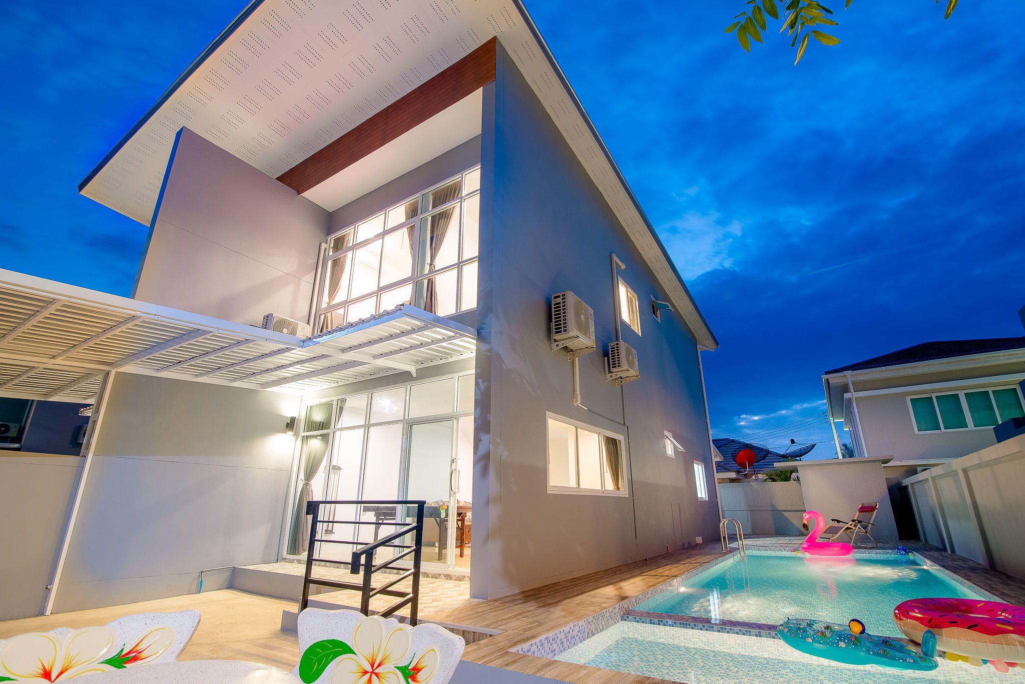 Une maison moderne dotée d’une piscine, d’un patio couvert et offrant une vue sur le ciel.