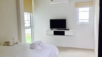 Ein Schlafzimmer mit einem Bett, einem an der Wand montierten Fernseher, einer Klimaanlage und einem Fenster.