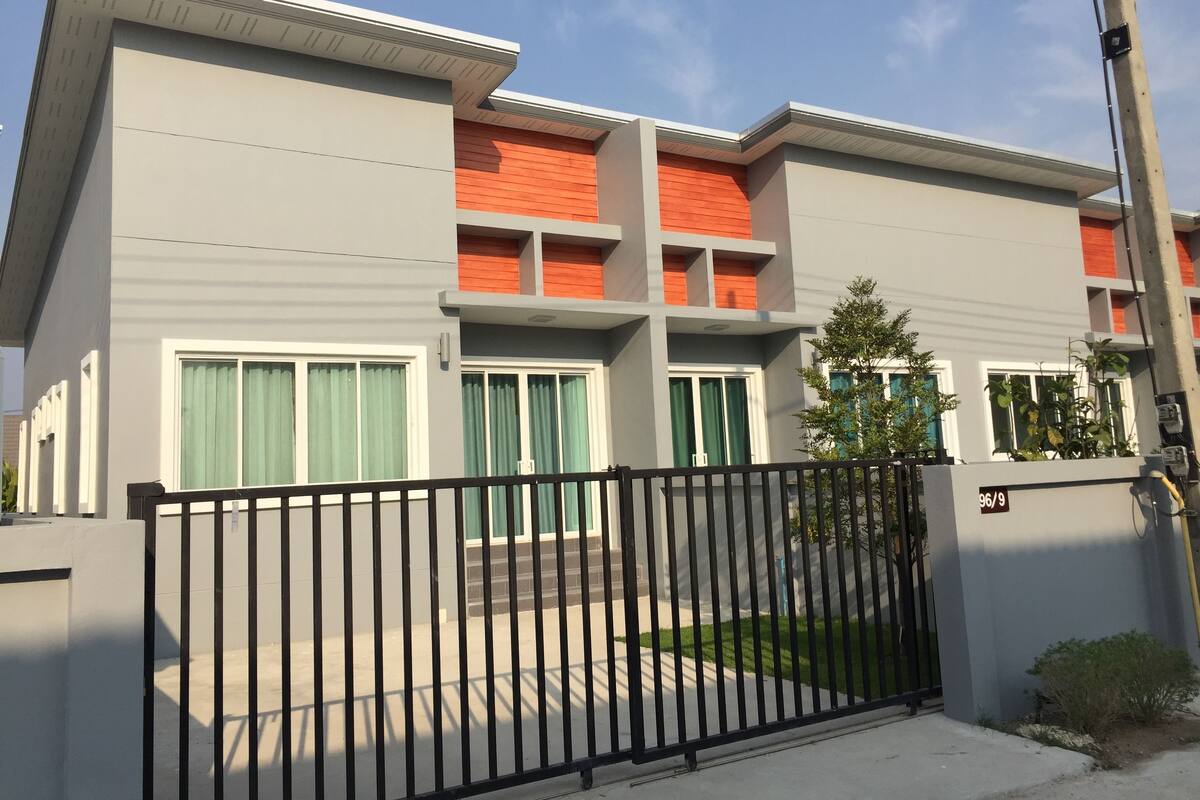 A modern building with a grey facade, red accents, and a black metal gate.