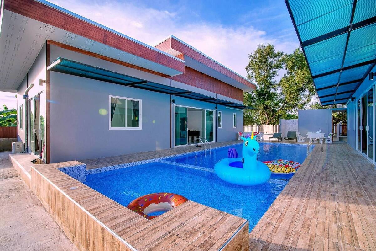 A modern house with a swimming pool, a wooden deck, and a covered patio area.