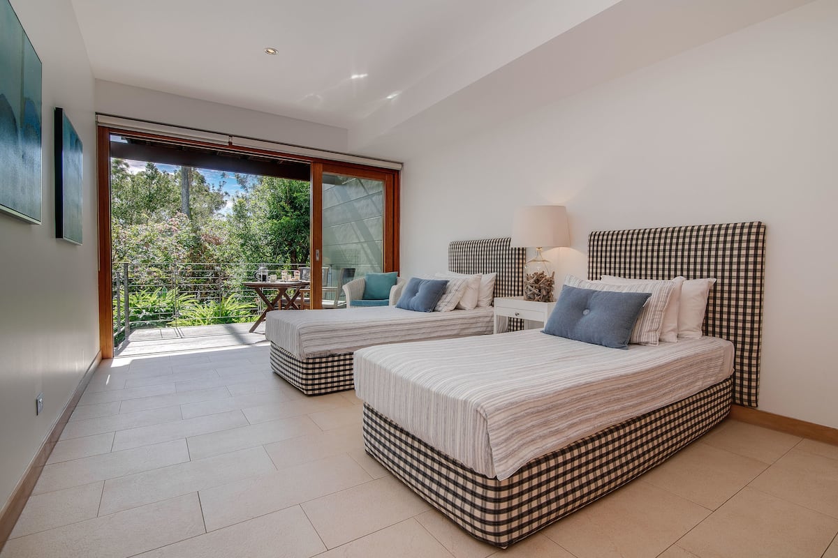 Une chambre avec deux lits, un balcon et une vue sur la verdure.
