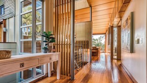 A modern interior with wooden flooring, a long hallway, and large windows.
