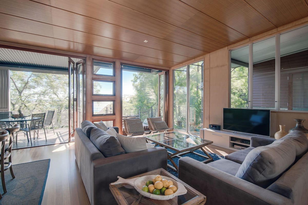 Un salon moderne comprenant un canapé, une table basse en verre, un téléviseur et un coin repas avec des chaises et une table.