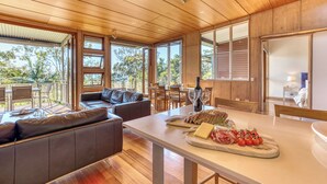 A modern kitchen with wooden cabinetry, a dining area with a table set for two, and a cozy seating area with a sofa.