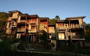 A multi-story residential building with balconies, a stone retaining wall, and a landscaped garden. - Noosa Residences (Noosa Heads)