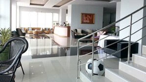 Una sala moderna con una escalera de cristal, un mostrador de recepción y un ventanal grande.