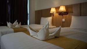 Habitación de hotel con dos camas, cada una con cubrecama blanco y una decoración de toallas. Hay dos lámparas de pared en el cabecero.