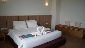 Una habitación de hotel con una cama grande, un banco de madera y una mesita de noche.