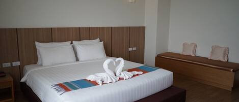 A hotel room with a large bed, a wooden bench, and a bedside table.