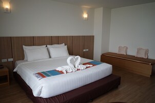 Una habitación de hotel con una cama grande, un banco de madera y una mesita de noche.
