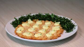 A plate of food with a creamy topping and garnished with green leaves.