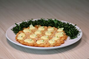 Un plato de comida con un topping cremoso y adornado con hojas verdes.