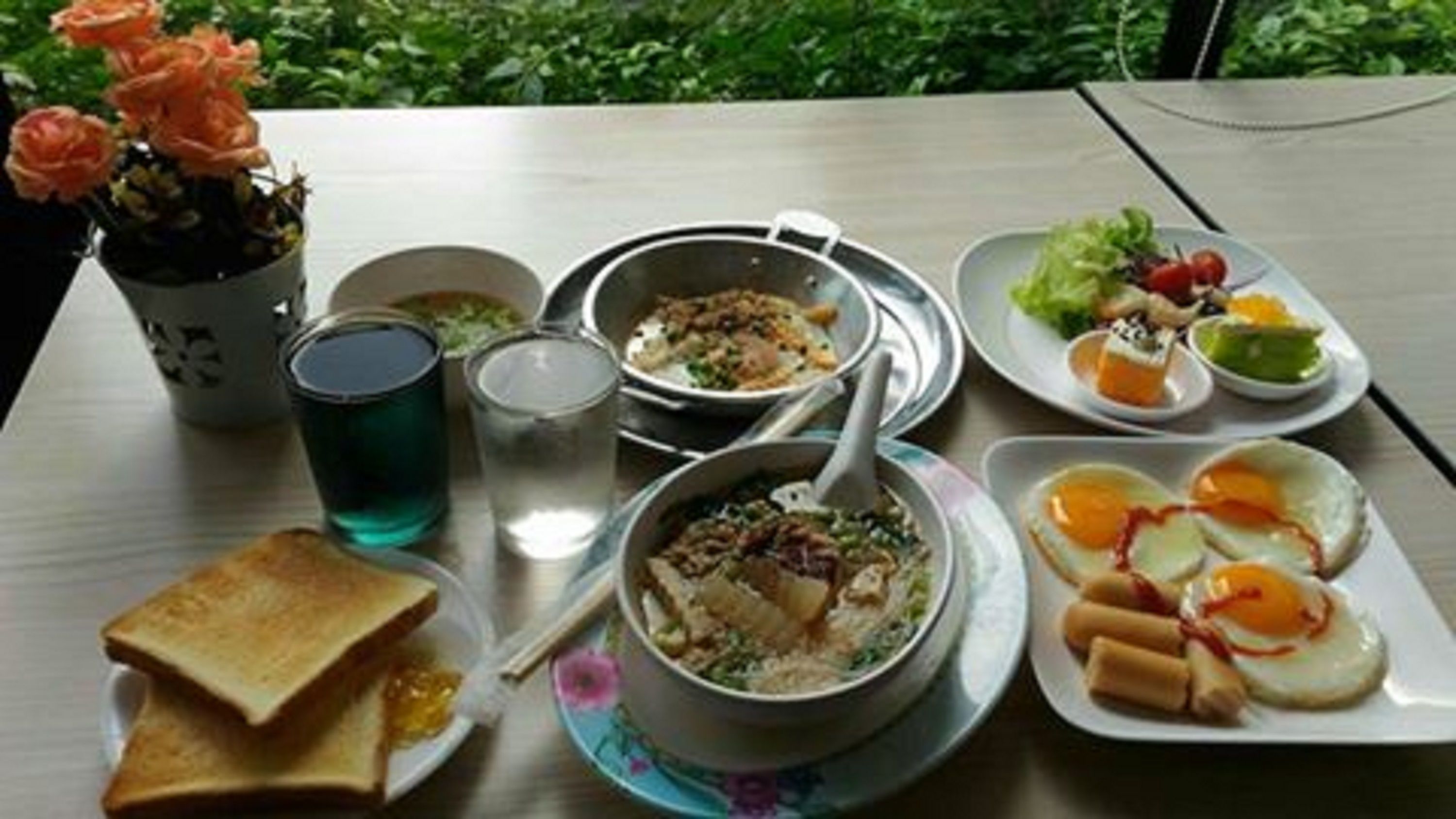 Una mesa con diversos platos, incluyendo un tazón de sopa, un plato de huevos, un plato de verduras, una taza de té y un vaso de agua.