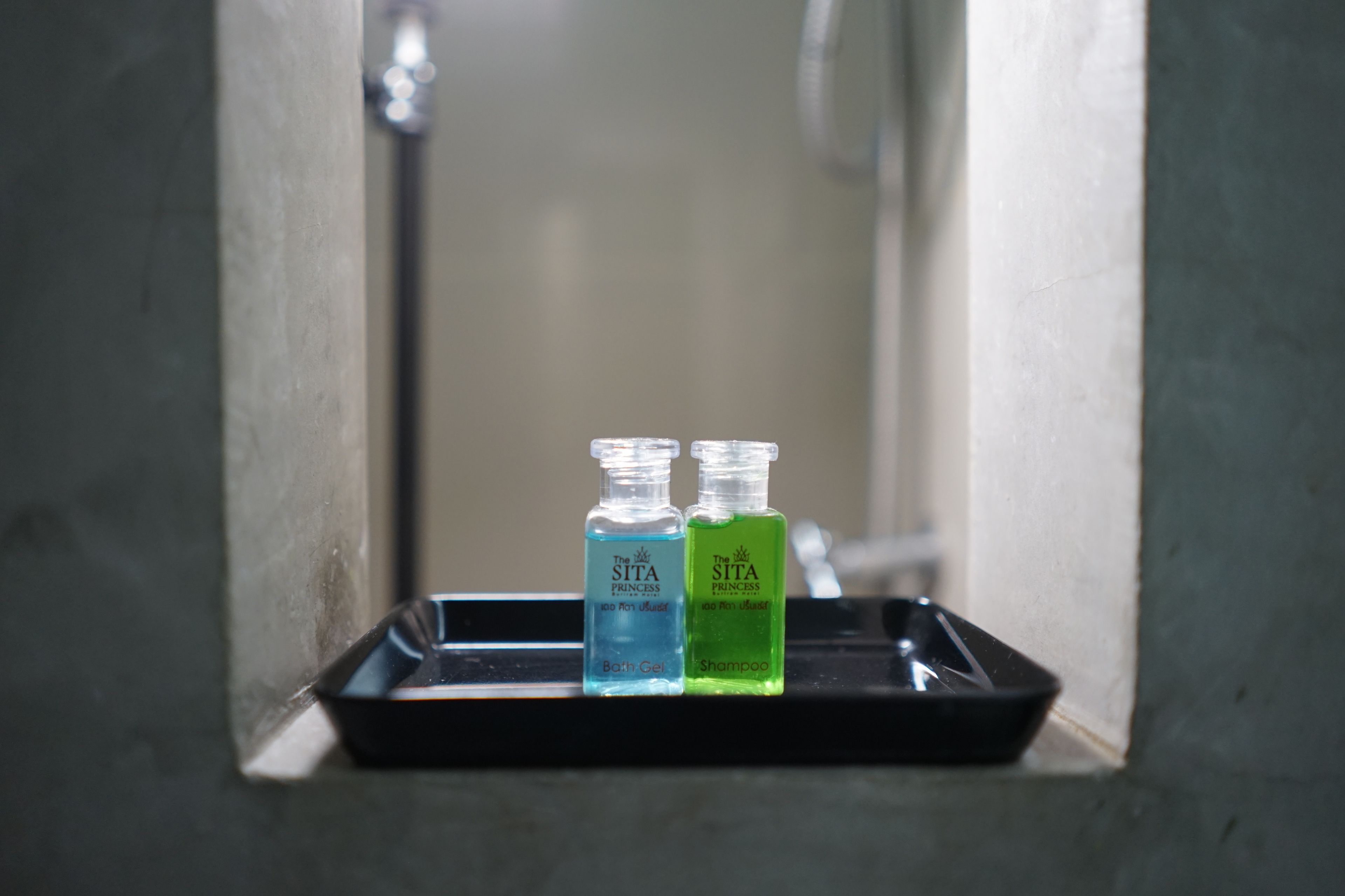 Two bottles of The Sita Princess bath gel and shampoo on a tray in a bathroom.