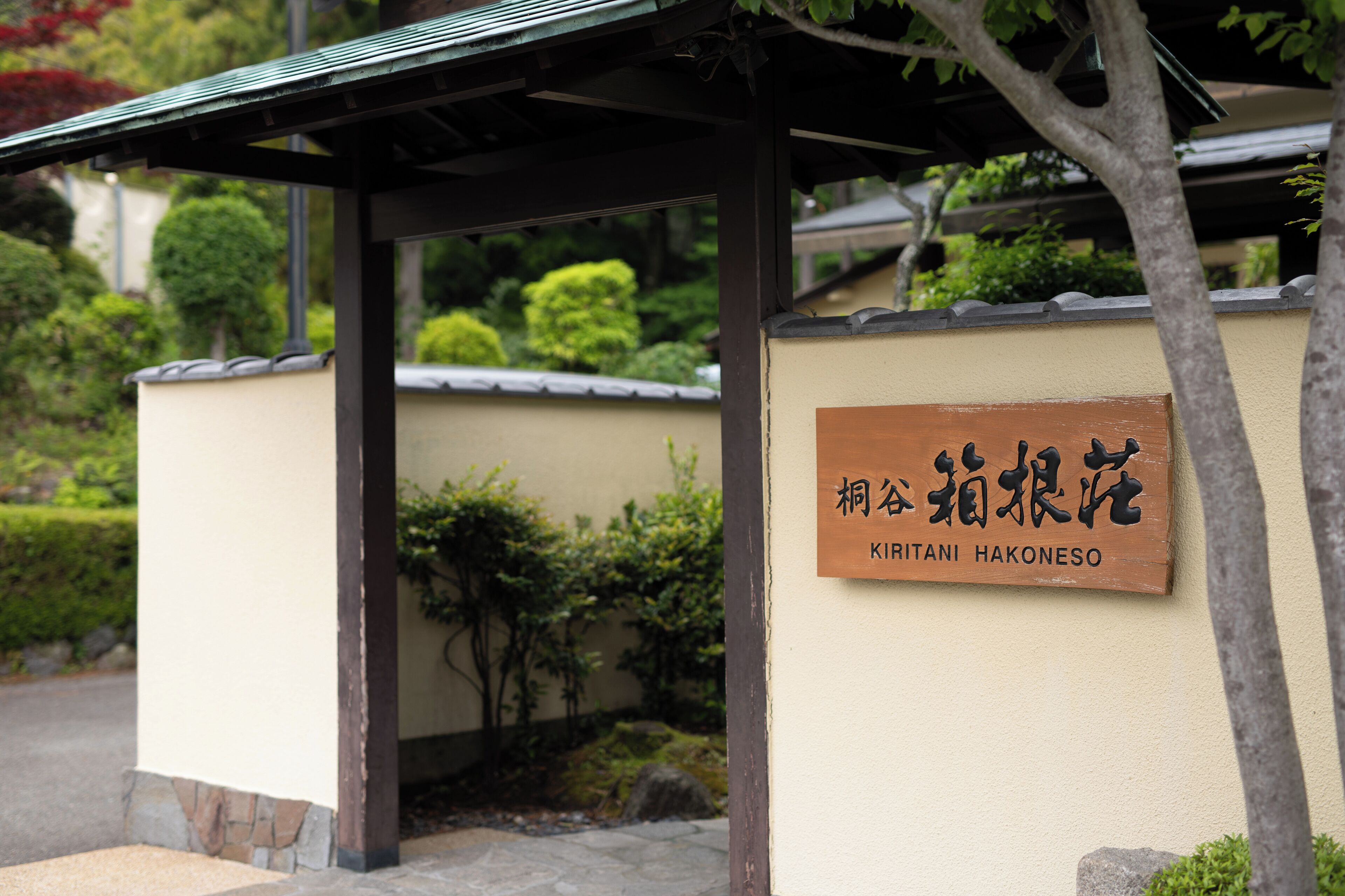 Un letrero de madera con caracteres japoneses y el texto en inglés 'KIRITANI HAKONESO', indicando un lugar.