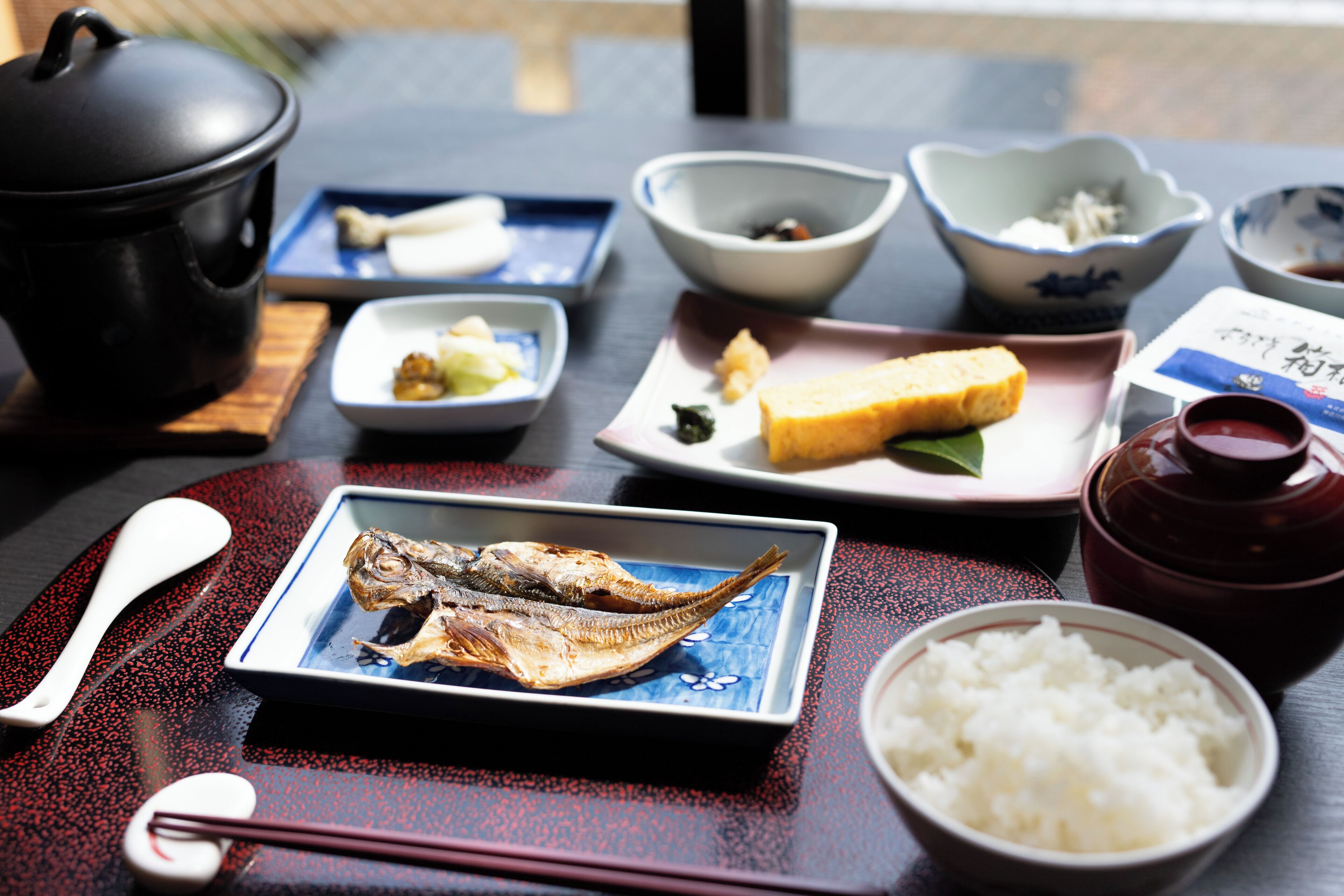 A table with various dishes including fish, rice, and a pot.