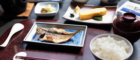 A table with various dishes including fish, rice, and a pot.